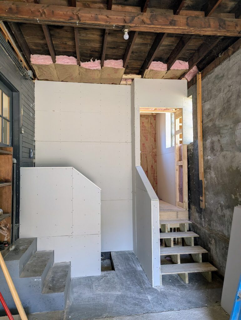 new mud room inside a garage. new drywall applied with new stairs